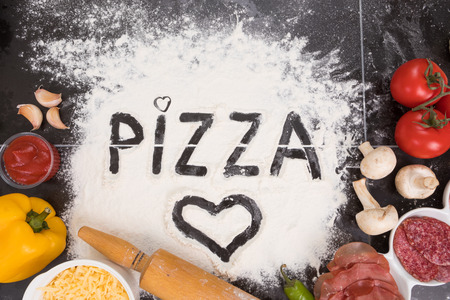 Ingredients for pizza, cheese, salami, mushrooms, tomatoes, peppers garlic tomato sauce and flourの写真素材