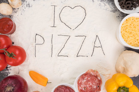 Ingredients for pizza, cheese, salami, mushrooms, tomatoes, peppers olives onion garlic dough tomato sauce and flourの写真素材