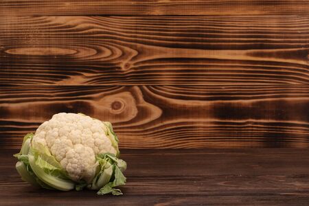 Fresh vegetables. White cauliflower with green leaves on wooden table with copy spaceの写真素材