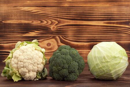 Assortment of cabbages on wood background. Fresh vegetables, broccoli, white cabbage and cauliflowerの写真素材