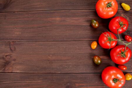 Delicious sweet cherry tomatoes of different colors and fresh tomatoes on rustic wooden surface with copy space. Juicy vegetables, bio foodの写真素材