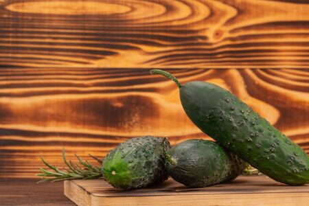 Cucumbers and rosemary leaves on cutting board with copy space. Fresh vegetables, healthy bio food conceptの写真素材