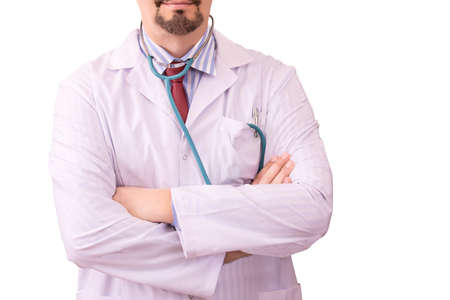 Confident doctor in a white dressing gown, tie and stethoscope keeps hands crossed, isolated on white background. His offers healthcare services and treats patients with Covid-19 in hospitalの写真素材