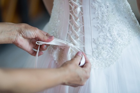Tying ribbons on a white wedding dressの写真素材