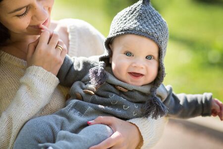 Happy young mother playing with little son in autumn parkの写真素材
