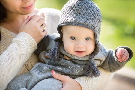 Happy young mother playing with little son in autumn parkの写真素材