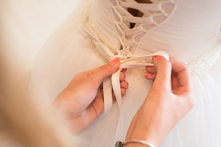 Tying ribbons on a white wedding dressの写真素材