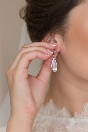 Beautiful earrings in the hands of a brideの写真素材