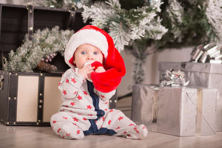 Beautiful little baby celebrates Christmas. New Year's holidays. Baby in a Christmas costume with giftの写真素材