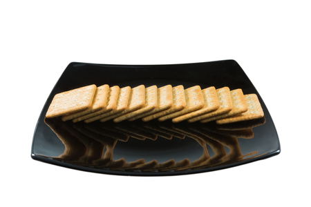 Cracker in black dish isolated on whiteの写真素材