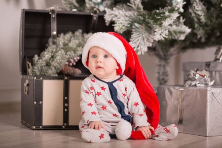 Beautiful little baby celebrates Christmas. New Year's holidays. Baby in a Christmas costume with giftの写真素材