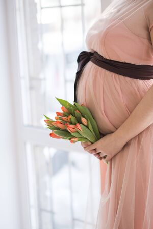 pregnant woman with tulip touching her bellyの写真素材