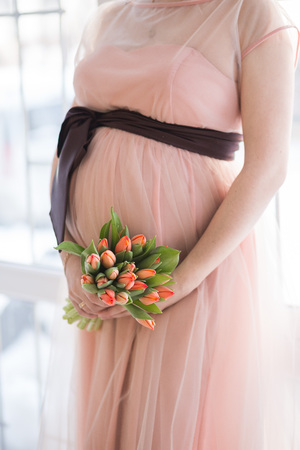 pregnant woman with tulip touching her bellyの写真素材