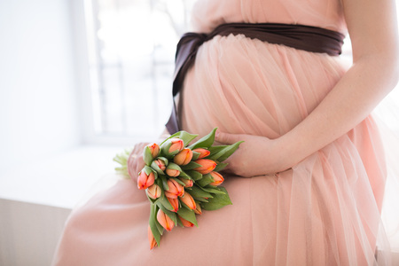 pregnant woman with tulip touching her bellyの写真素材