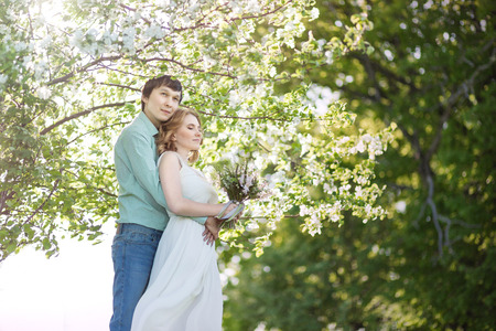 Love couple standing among blooming apple tree, springの写真素材