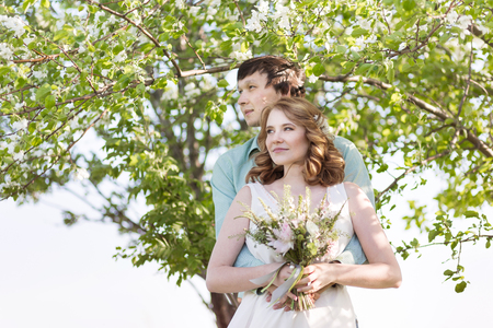 Love couple standing among blooming apple tree, springの写真素材