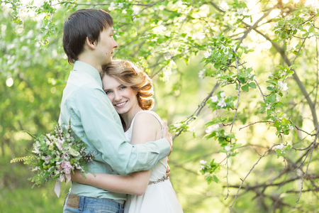 Love couple standing among blooming apple tree, springの写真素材