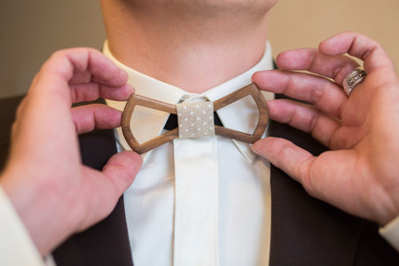 Man's hands touches Wooden  bow-tie on a suitの写真素材