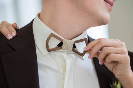 Man's hands touches Wooden  bow-tie on a suitの写真素材