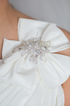 A close up of a wedding dress with a large silk bowの写真素材