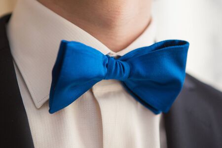 Man's hands touches bow-tie on a suitの写真素材