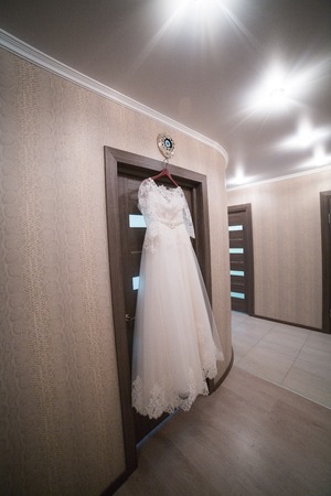 The wedding dress on a hanger in the room of the brideの写真素材