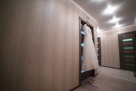 The wedding dress on a hanger in the room of the brideの写真素材