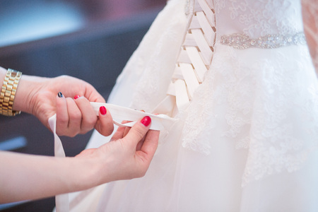 Tying ribbons on a white wedding dressの写真素材