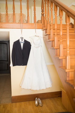 bride's dress and groom's suit hanging in yardの写真素材