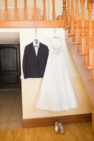 bride's dress and groom's suit hanging in yardの写真素材