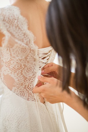 Tying ribbons on a white wedding dressの写真素材