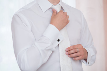 groom tying his tie in the morning of the wedding day