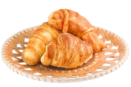 Croissants in wicker wooden plate isolated on white backgroundの写真素材