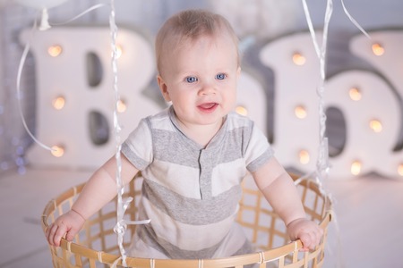 Portrait of a crawling baby on the decorative basket with balloonsの写真素材