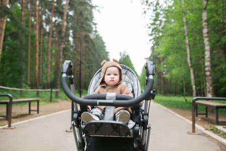 Baby in sitting stroller on nature. Adorable one year-old child with a stroller walk in a green summer forestの写真素材