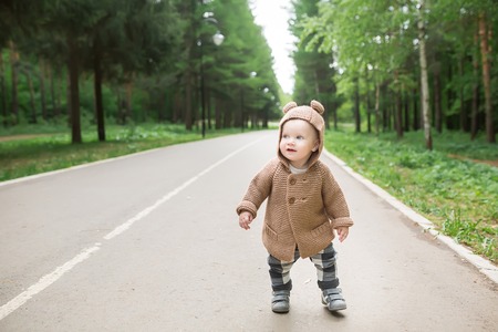 A one year old baby boy taking some of his first steps outdoors in spring park. Cute toddler walking in the green forest in summerの写真素材