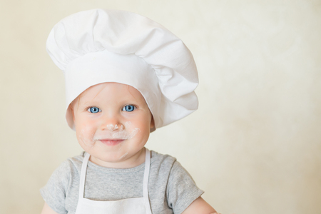 Portrait of the little boy in a suit of the cook sculpts dough. Baby make dinner in chef suit. Cooking concept with free text space - copy spaceの写真素材