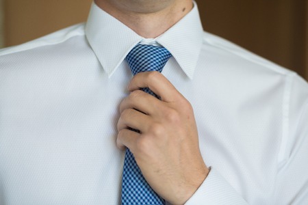 Businessman in white shirt tying the blue necktieの写真素材