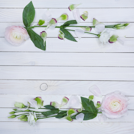 Top view of floral wreath frame - Free text space concept. Vintage white wooden background with free a sheet of paper for text. Beautiful romantic composition with flowersの写真素材