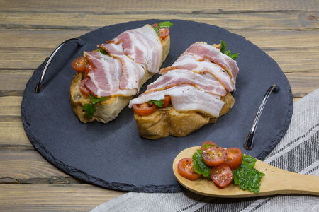 Bruschetta with bacon, tomatoes, herbs and oil on toasted garlic cheese bread ciabattaの写真素材