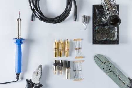 Top view of Tools for home electrical repair - soldering iron, cable, solder, tin, soldering iron stand, resistor, Jack 3.5, xlr, rca, diode, pliers, scissors, cable stripper, multimeter. Flat layの写真素材