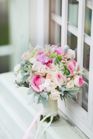Rich bunch of pink peonies and lilac eustoma roses flowers, green leaf in the window. Fresh spring bouquet. Summer Backgroundの写真素材