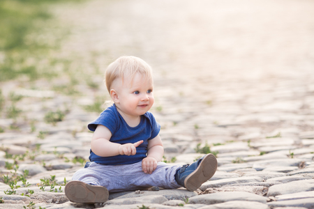 Happy cute boy on old roadway. Smiling one child outdoors on Road paved with stone on the sunsetの写真素材