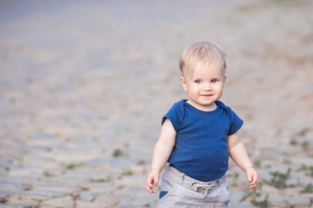 Happy cute boy on old roadway. Smiling one child outdoors on Road paved with stone on the sunsetの写真素材