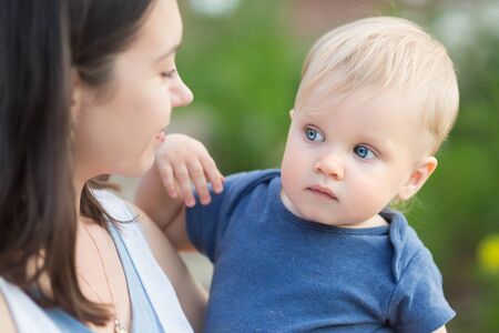 Portrait of happy loving mother and her babyboy outdoors. Mom holding her child in the parkの写真素材