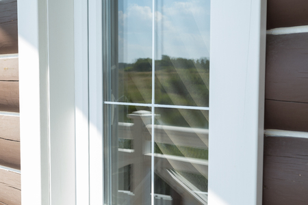 Plastic white window muntin bars with the reflection of the blue cloudy sky with green treesの写真素材