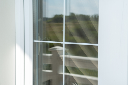 Plastic white window muntin bars with the reflection of the blue cloudy sky with green treesの写真素材