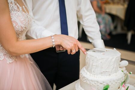 Bride and Groom at Wedding Reception Cutting the white Wedding Cakeの写真素材