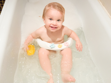 A little 1,5 year-old baby boy playing with toys in a bubble bath. Cute kid washing with foam in bathtubの写真素材