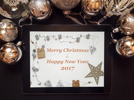Christmas and New Year background with decorations and silver balls on dark board with tablet with Merry Christmas and happy new year text, top view, flat layの写真素材